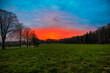 Bright red sunset Over meadows at the edge of a forest next to a road near Koblenz