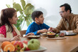 Happy Indian family in traditional cloth, father daughter and son chatting happily over meal, family enjoying tasting Indian food, selective focus
