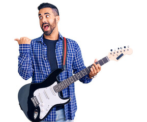 Poster - Young hispanic man playing electric guitar pointing thumb up to the side smiling happy with open mouth