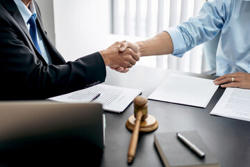 Wall Mural - Handshake after good cooperation, Two people shaking hands after discussing contract agreement on front a judge's gavel