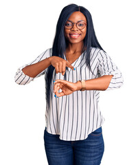 Canvas Print - Young african american woman wearing casual clothes and glasses in hurry pointing to watch time, impatience, upset and angry for deadline delay