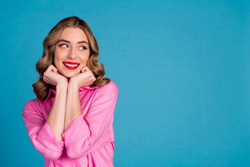 Poster - Photo of lovely young lady dreamy fists touch cheeks look empty space dressed stylish pink garment hairdo isolated on blue color background