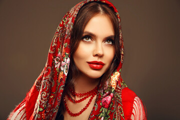 Wall Mural - Russian girl Matryoshka style. Fashion woman portrait with traditional red headscarf. Beauty girl model with red lips makeup isolated on studio background.