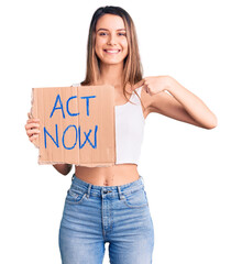 Wall Mural - Young beautiful girl holding act now banner pointing finger to one self smiling happy and proud