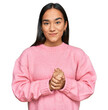 © Krakenimages.com - Young asian woman wearing casual winter sweater with hands together and crossed fingers smiling relaxed and cheerful. success and optimistic
