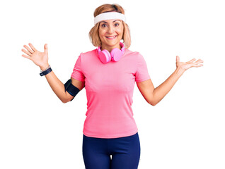 Sticker - Young blonde woman wearing sportswear and headphones celebrating victory with happy smile and winner expression with raised hands