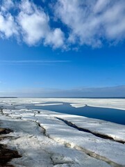 Wall Mural - Frozen sea coast, ice at the sea, sea horizon, sky reflection on the water surface, natural colors