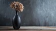 A black vase with a dried flower inside. Suitable for home decor