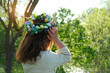 Girl in decorative Spring wreath in garden, natural background. rear view. Floral crown with eggs, symbol of Easter, Ostara holiday. festive decor for spring season. ceremony for wiccan Ostara sabbat