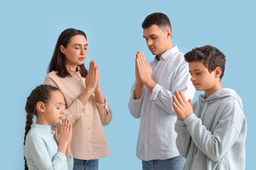 Wall Mural - Family praying together on blue background