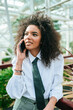 Woman with tie and afro hair using mobile phone in garden