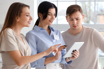 Sticker - Real estate agent with young couple using tablet computer in new house