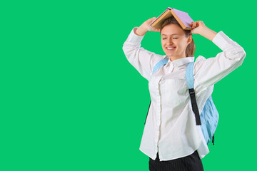 Poster - Female student with book on her head against green background. End of school concept