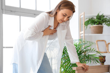 Poster - Mature woman suffering from chest pain at home. Menopause concept