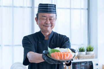Wall Mural - The salmon slice is in the hands of the chef. Asian chef slice salmon by knife.