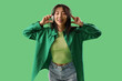 Asian young woman listening music in headphones on green background