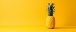   A pineapple sits atop a yellow table alongside a green leafy plant also positioned on the same yellow table