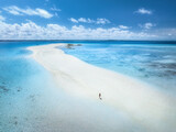 Fototapeta Do pokoju - Aerial view of alone young woman on the sandbank in ocean, white sand, blue sea during low tide at sunny summer day in Nakupenda, Zanzibar island. Top view of girl, sand spit, water, sky with clouds