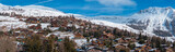 Fototapeta Miasta - Aerial panoramic view of the Verbier ski resort town in Switzerland. Classic wooden chalet houses standing in front of the mountains. 