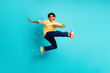 Full length photo of good mood guy dressed yellow t-shhirt jumping in sunglass headphones at party isolated on turquoise color background