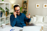 Fototapeta Panele - Young happy man talking on the phone in home office