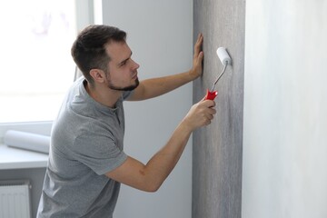 Poster - Man hanging stylish gray wallpaper in room