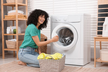 Canvas Print - Happy woman with laundry near washing machine indoors