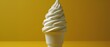   A white ice cream cone sits atop a yellow table beside a black-and-white mug with a straw protruding from it