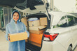Asian businesswoman driving delivery running business online ordering wholesale retail online logistics wearing raincoat delivering parcel boxes in the rainy season to customers in front of the house.