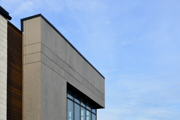 Wall Mural - The exterior wall of a contemporary commercial-style building with aluminum metal composite panels and glass windows. The futuristic building has engineered diagonal cladding steel frame panels.