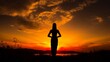 Yoga practitioner in silhouette, meditating with hands in prayer position against the backdrop of a vibrant sunset, symbolizing peace and tranquility.