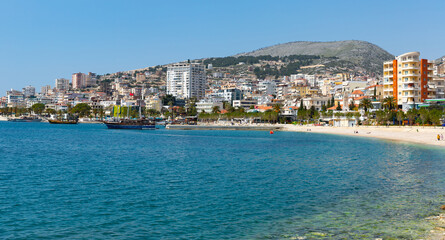 Wall Mural - Scenic view of modern cityscape of Sarande on shore of open blue bay of Ionian Sea on sunny spring day, Albania..