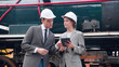 Young caucasian engineer man and woman in suit checking train with tablet in station, team engineer inspect system transport, technician examining infrastructure, transportation and industry.