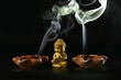 Close-up of a little Buddha statue with the smoke of an extinguished candle  on the back background