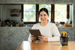 © Chanakon - Young asian beautiful business woman working with tablet sitting at home. Smiling charming happy young female doing homework meeting conference with team at home.