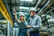 © SKW - Two people in a factory, one pointing at a laptop. The woman is wearing a hard hat and the man is wearing a gray shirt