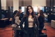 © Flamingo Images - Young businesswoman standing in an office lobby with colleagues working behind her.