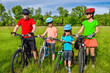 Family on bikes cycling outdoors, active healthy parents and kids riding bicycles, family sport and fitness concept
