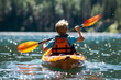 young boy rowing in a kayak on the lake, back view