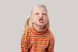 Cute little girl with blond hair in a striped t-shirt is yawning.