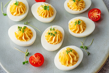 Wall Mural - Deviled eggs with cheese, mustard and microgreens on top on a plate for Easter.