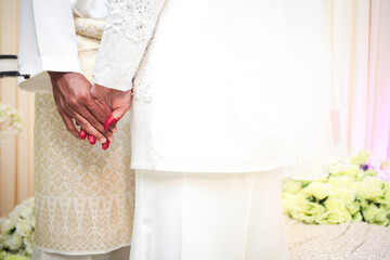 Wall Mural - Young married couple holding hands, ceremony wedding. Malay wedding reception.