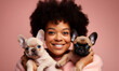 Close up shot of pleased girl with Afro hair holds two puppies, spends leisure time with loyal animal friends