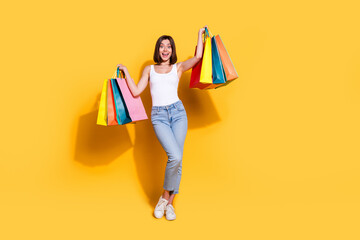 Poster - Full body photo of attractive young girl hold shopping bags wear trendy white outfit isolated on yellow color background