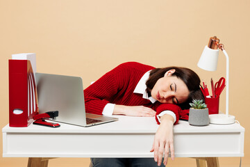 Wall Mural - Young sad exhausted employee business woman wear red sweater shirt sit work at office desk with pc laptop put head on table sleep isolated on plain pastel beige background. Achievement career concept.