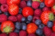 Variety of berries - trawberries, blueberries, raspberries scattered as a full background, top view