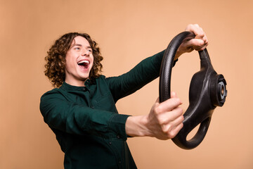 Poster - Photo portrait of handsome young guy hold steering wheel dressed stylish green garment isolated on beige color background