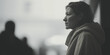 Monochrome side profile of a contemplative woman in a coat, set against a blurred urban background