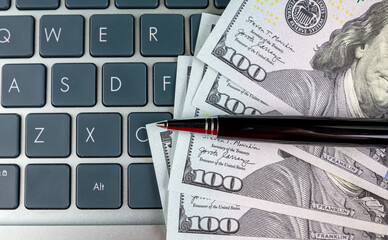 Wall Mural - dollars and a pen lie on the laptop keyboard