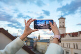 Fototapeta Las - Female hands holding smartphone and making photos in Lviv